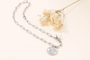 Silver paperclip chain necklace with cupid angel coin pendant and a small pearl accent