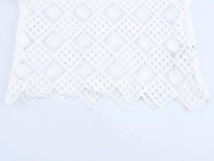 Detail of white hollow lace top showing geometric diamond pattern and wavy scalloped hem