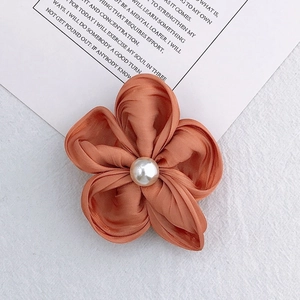 Detailed view of handmade coral satin flower accessory with a centered pearl embellishment