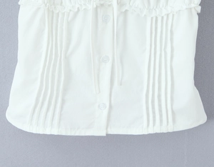 Detail showing white fabric texture with round buttons and elegant pleated ruffles on top