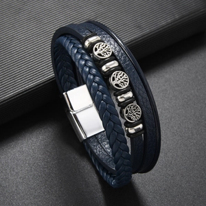 Gros plan sur les breloques arbre de vie du bracelet en cuir tressé bleu