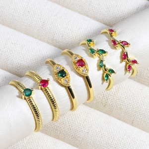 Detailed display of assorted gold-plated rings with red and green cubic zirconia settings