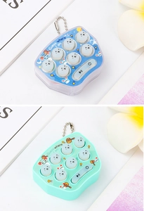 Close-up of mini blue and green whack-a-mole game keychains with metal chains