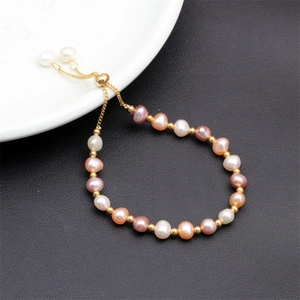 Detailed macro view of colorful freshwater pearl bracelet with gold beads on ceramic tray