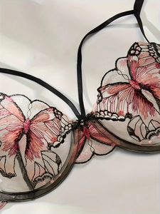 Close-up of mesh bra with intricate pink and black butterfly embroidery and straps