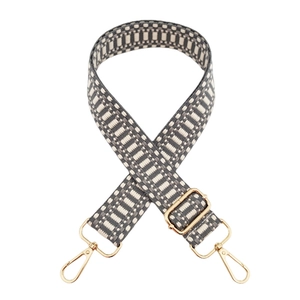 Detail of adjustable woven purse strap with grey and beige geometric patterns and gold metal hooks