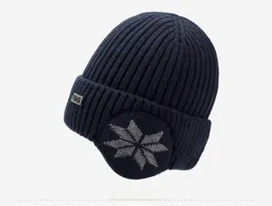 Detail of navy knit beanie with ear flaps, snowflake pattern, and FBKS metal logo