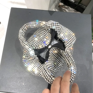 Macro detail of luxury rhinestone mini bucket bag with knotted handle and magnetic closure