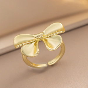 Macro shot of an adjustable gold bow ring with a polished metallic finish on a pedestal
