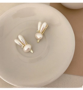 Detail view of pearl rabbit hair clips with gold metal base on a minimalist background