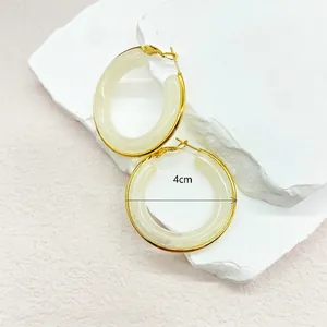 Detail view of 4cm gold stainless steel hoop earrings with white resin inlay