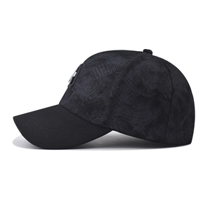 Detail shot of black camo fabric texture and embroidered badge on the baseball cap