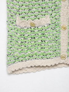 Detail of green wavy knit texture with cream ribbed trim and gold embossed buttons