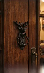 Détail du heurtoir de porte vintage en fonte avec tête de cerf sur bois sombre