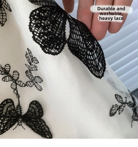 Detail of durable heavy-duty lace fabric with embroidered black butterfly on canvas bag