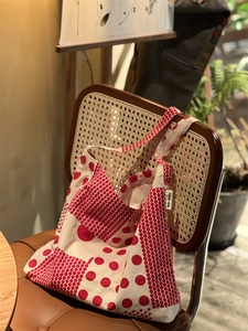 Gros plan du sac en toile à pois rouges avec étiquette de marque sur une chaise vintage