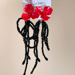 Détail de boucles d'oreilles fleur rouge avec longues pampilles en cristal noir
