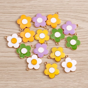 Close-up of colorful enamel daisy charms with gold borders on a wooden background