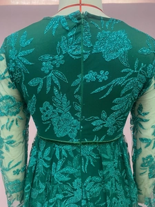 Detailed close-up of emerald sequin embroidery and mesh lace on long sleeve evening gown