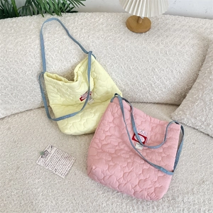 Detail of heart-shaped quilted texture on cotton tote bag with blue straps