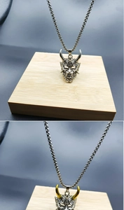 Detailed comparison of silver and gold-horned bull skull pendants on wooden blocks