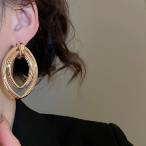 Close-up of gold layered oval metal earrings shown on a model for a stylish look