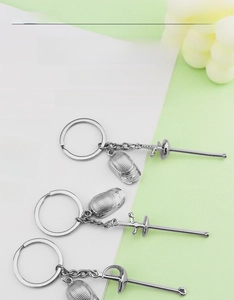 Detail of silver zinc alloy fencing mask and foil sword pendants on stylish keychains