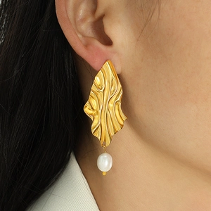 Elegant gold wavy textured earrings with baroque freshwater pearls shown on model