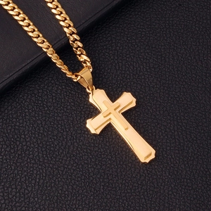 Detailed shot of golden cross pendant on cuban chain over black leather background