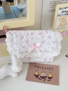 Detailed close-up of quilted floral crossbody bag with lace edges and pink silk bow