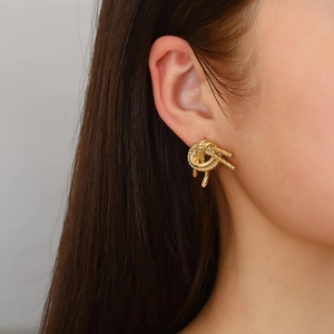 Fashionable 18K gold wheat ear knot earrings worn by a model on a light background