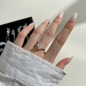 Close-up of a heart-shaped zircon ring in gold finish on female hand model