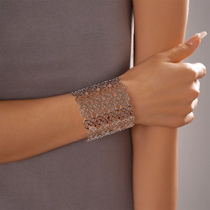 Dettaglio di un bracciale rigido color argento con motivi floreali geometrici traforati