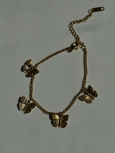 Detail of adjustable gold butterfly charm bracelet with textured wings and lobster clasp