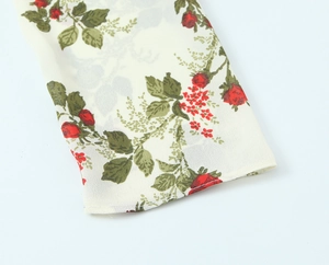 Close-up of floral print chiffon sleeve cuff with delicate stitching on off-white fabric