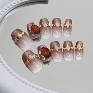 Cat eye press-on nails with gradient brown finish and amber rhinestone accents