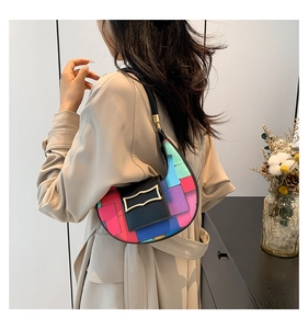 Detail of a crescent shoulder bag with colorful geometric patterns on a beige trench coat