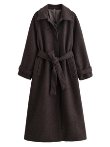 Detail of dark brown wool coat showing waist belt texture and long sleeve tailoring