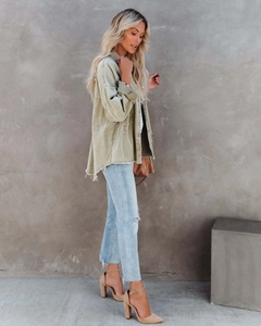 Detail of sage green oversized denim jacket with raw edges and distressed texture