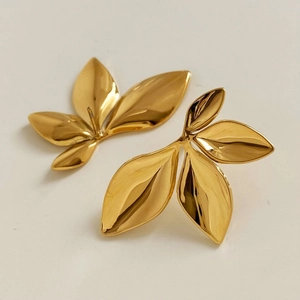 Detailed view of gold-plated leaf earrings with a 3D twisted design and polished finish