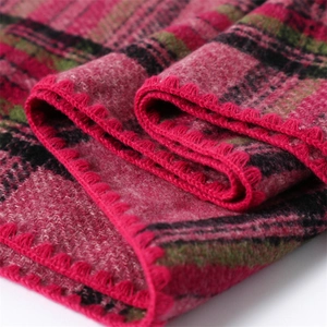 Macro detail of red and green plaid cashmere-like scarf showing soft knit texture and stitching