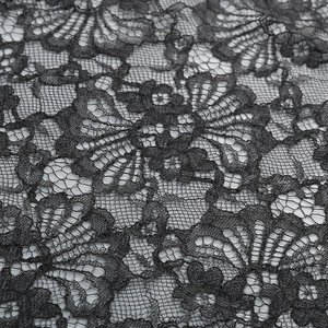 Close-up of black floral lace fabric showing intricate mesh patterns and fiber texture