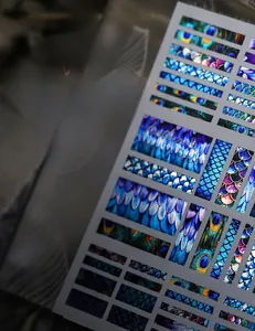 Macro shot of EM series metallic nail decals featuring peacock and fish scale textures