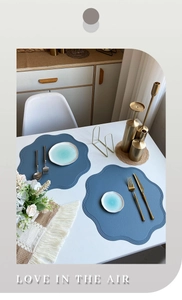 Close-up of blue scalloped PU leather placemats on a dining table with elegant decor