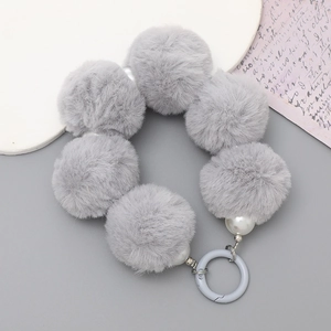 Detail of grey faux fur pom pom charm with white pearls and plastic clasp for handbags