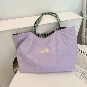 Close-up of lavender tote bag featuring a logo patch and stylish plaid shoulder straps