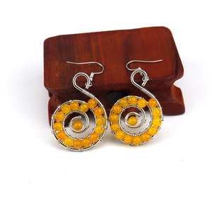 Detailed macro shot of handmade spiral wire earrings with orange crystal beads on wood