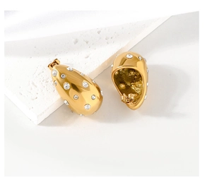 Close-up of gold-plated teardrop earrings with sparkling rhinestones on stone base
