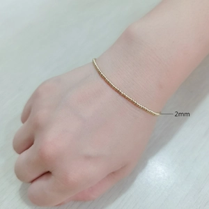 Detail of 2mm minimalist gold beaded stainless steel elastic bracelet on a wrist