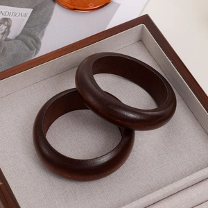 Macro detail of two polished dark brown sandalwood bangles on a display tray